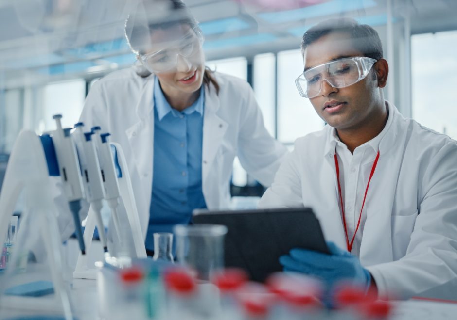 Modern Medical Research Laboratory: Two Scientists Working Together Analysing Samples, Discussing Innovative Technology. Advanced Scientific Lab for Medicine, Biotechnology, Molecular Biology