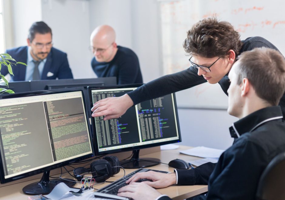 Startup business and entrepreneurship problem solving. Young AI programmers and IT software developers team brainstorming and programming on desktop computer in startup company share office space.